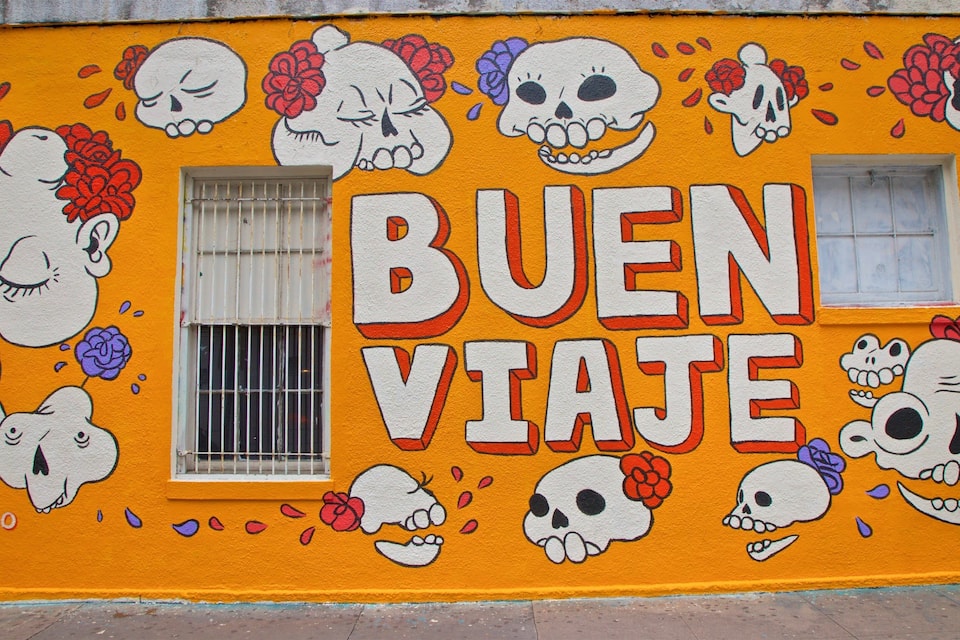 A wall with a mural featuring skulls and flowers, and the text 'BUEN VIAJE' written in large letters.