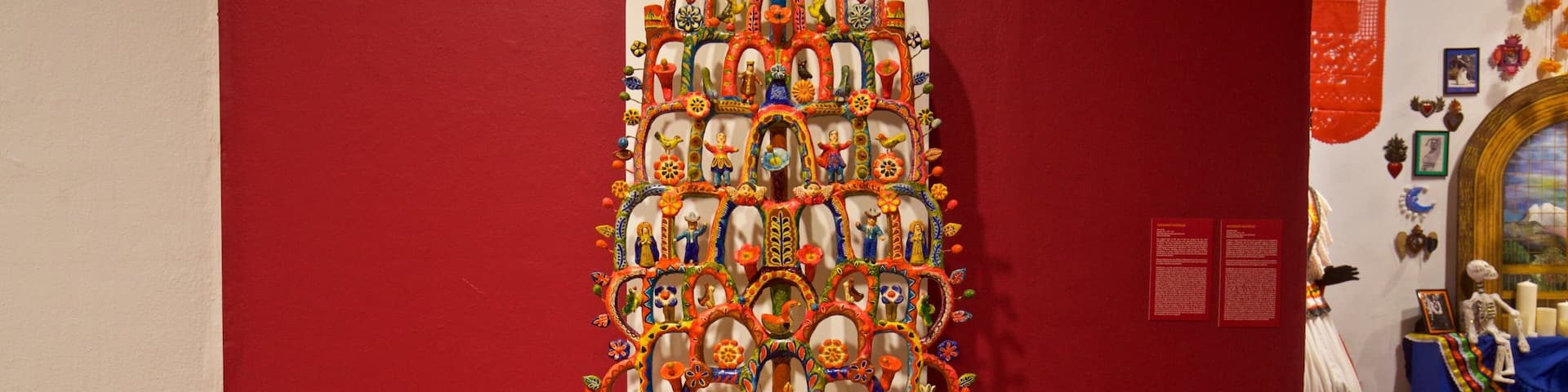 A colorful, intricate wall art installation with a central tree motif, surrounded by various figures and patterns.