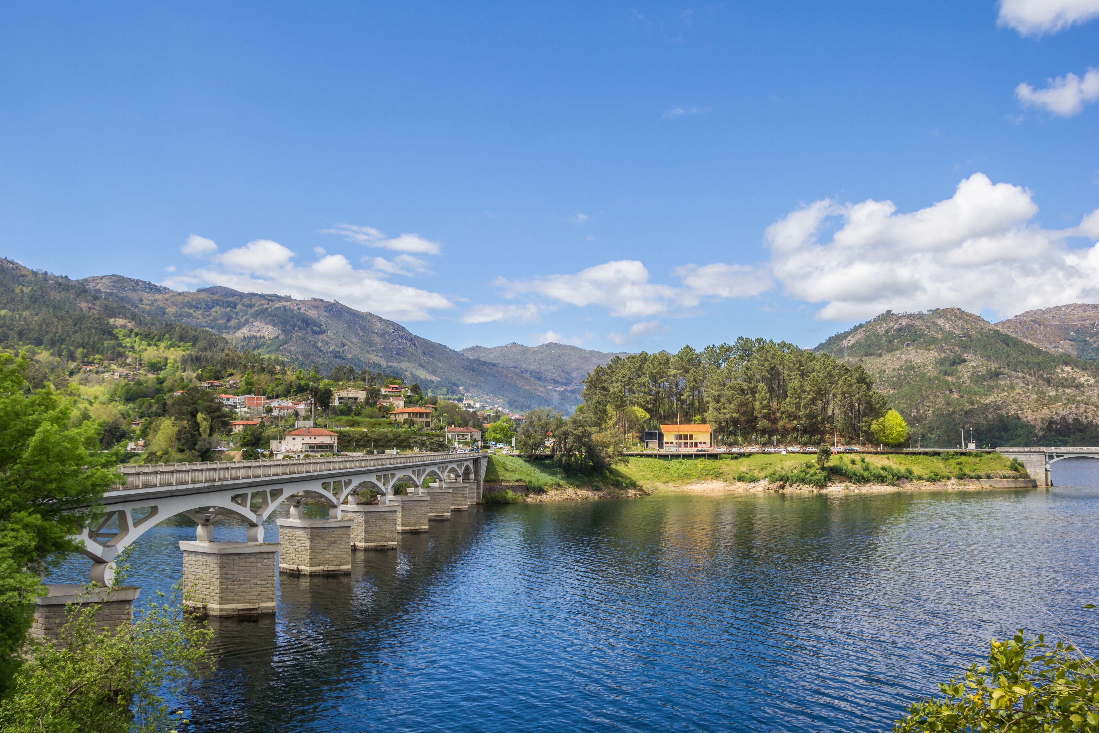 A stone bridge over a river, surrounded by mountains and houses.