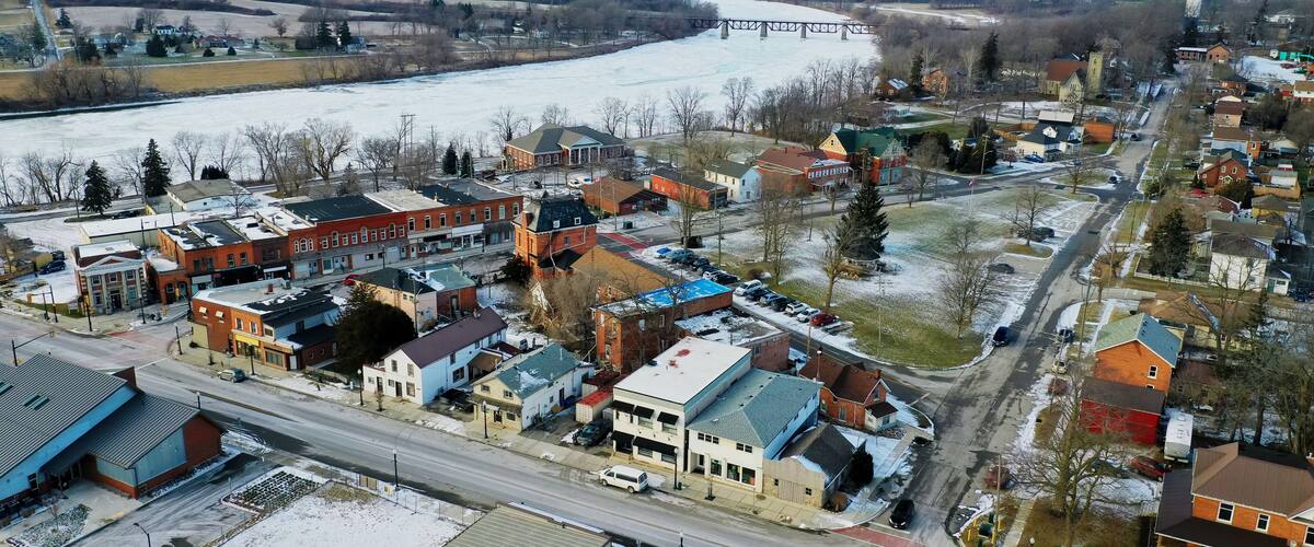 A snow-covered town with a river, a bridge, and various buildings.