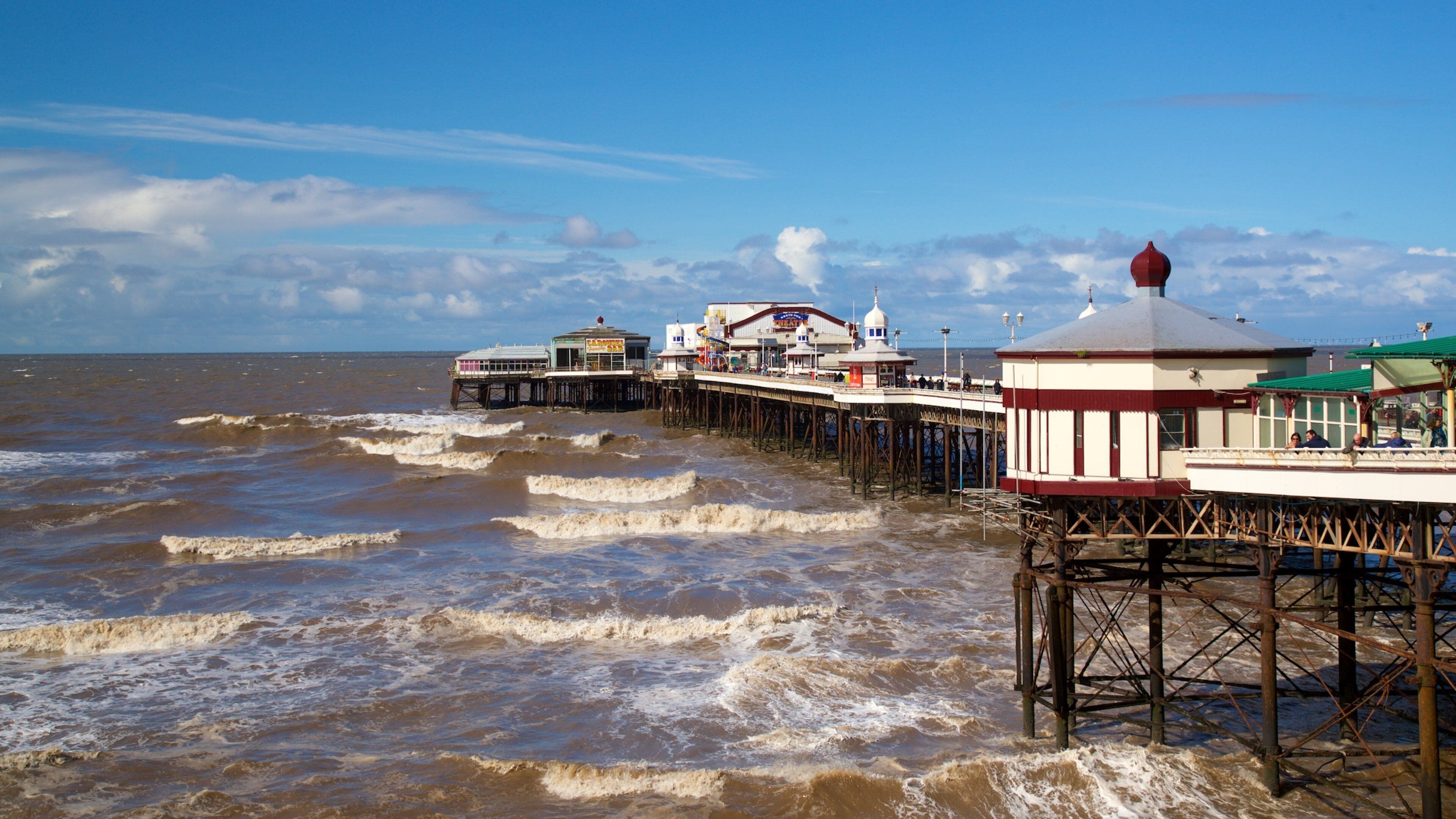 A pier with buildings and a lighthouse by the sea.
