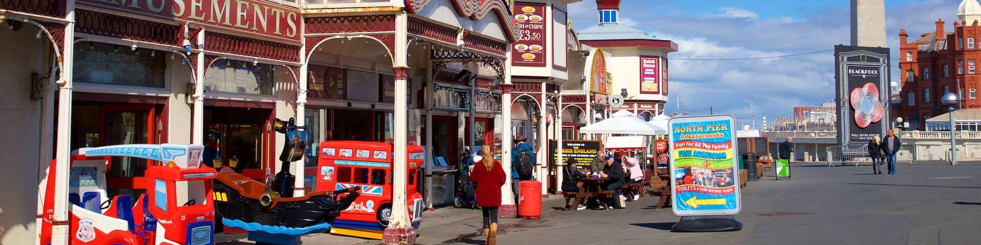 A street with a Ferris wheel, a sign for North Pier Amusements, and a large monument in the background.