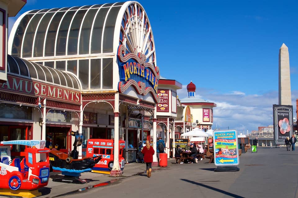 A street with a Ferris wheel, a sign for North Pier Amusements, and a large monument in the background.