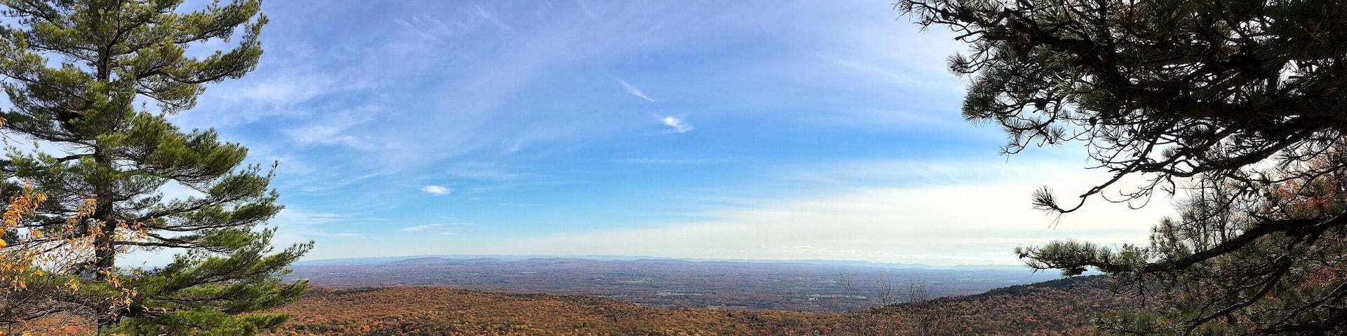A mountainous landscape with autumn foliage, rocky terrain, and a clear sky.
