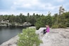 A person sitting on a rock by a lake surrounded by trees.
