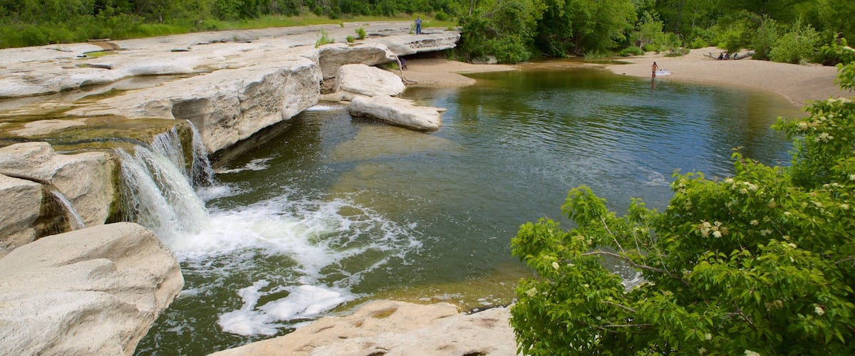 A natural landscape with a waterfall, rocky terrain, and a river.