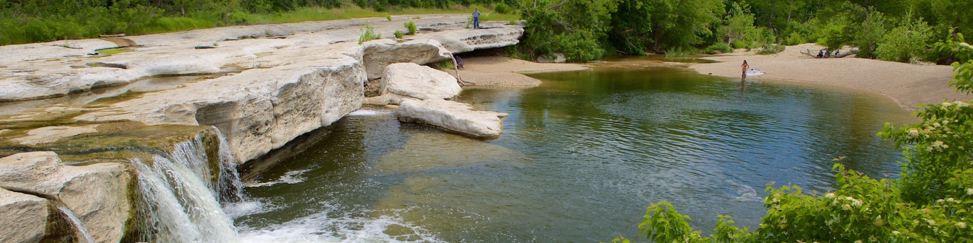 A natural landscape with a waterfall, rocky terrain, and a river.