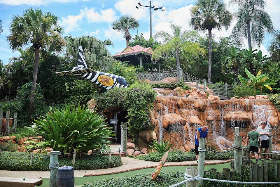 A tropical theme park with a waterfall, palm trees, and a ride called Congo River.