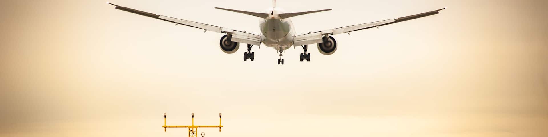 Commercial airplane landing at sunset. Runway approach lights. Concept for transport,transportation,travel,aviation,vacation,business travel,freedom,reaching destination,speed. Shot at Milan Malpensa