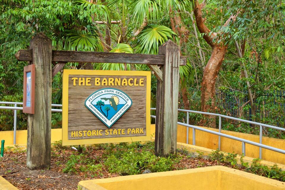 A sign for The Barnacle Historic State Park with a Florida Park Service emblem.