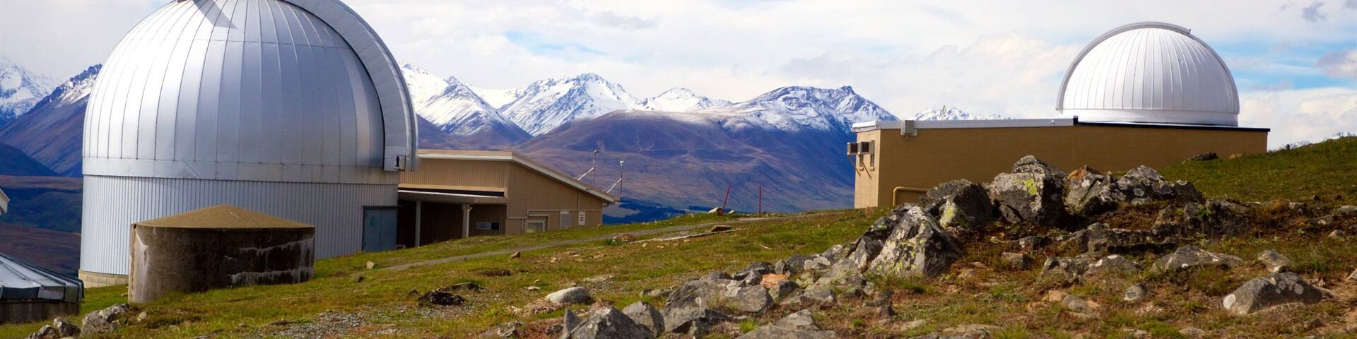 A mountainous landscape with two large domed observatories and a building in the foreground.