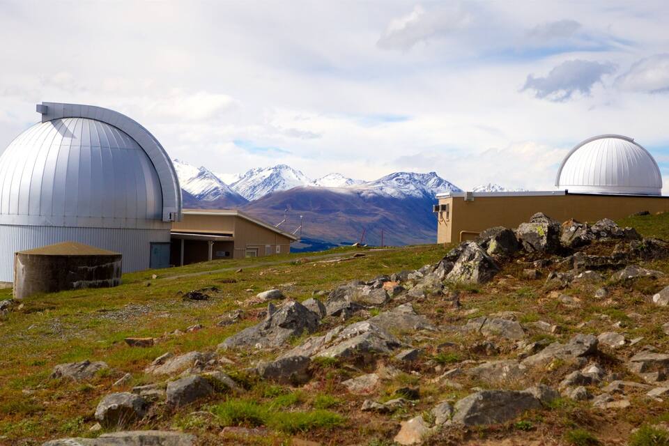 Un paisaje montañoso con dos grandes observatorios abovedados y un edificio en primer plano.