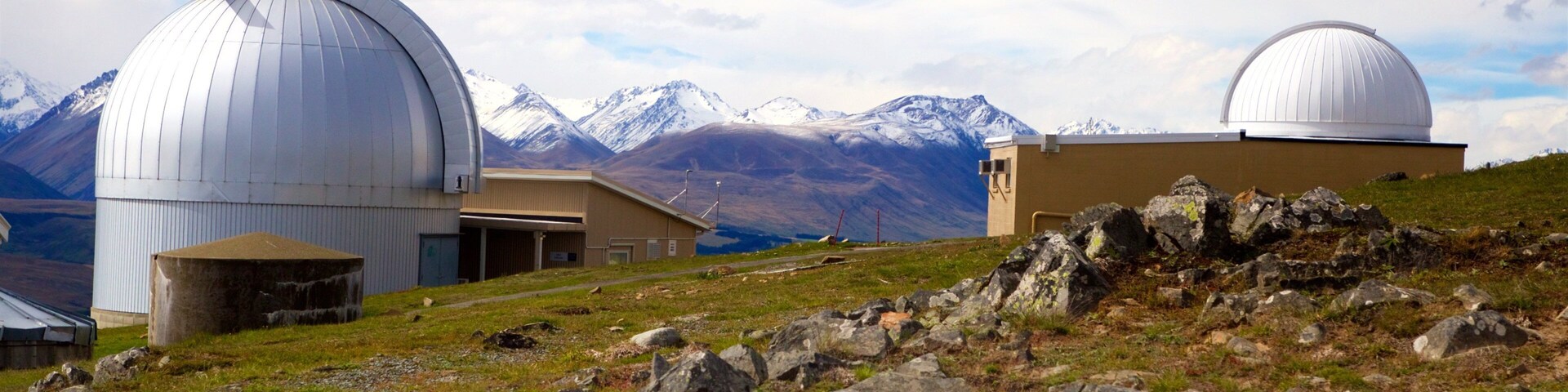 Un paisaje montañoso con dos grandes observatorios abovedados y un edificio en primer plano.