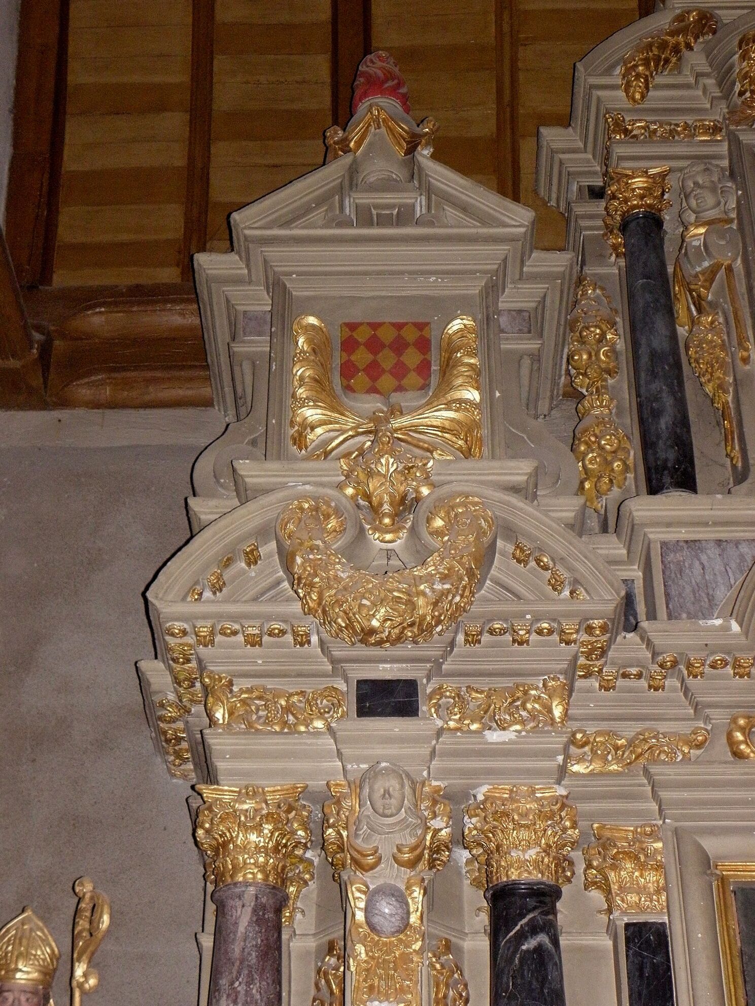 A detailed architectural model with ornate golden decorations, a central emblem, and marble columns.