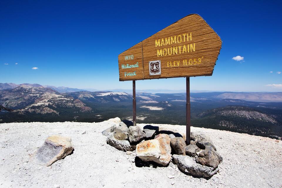 A wooden sign at Mammoth Mountain's summit with the text "Mammoth Mountain Inyo National Forest" and "Elevation 11,053 ft."