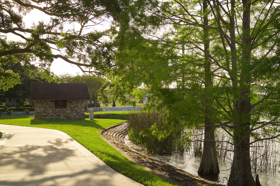A stone building, a pathway, and a body of water with trees.