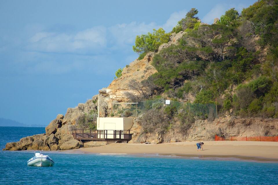 Eine Küstenlandschaft mit einer felsigen Klippe, einem Strand und einem Boot im Wasser.