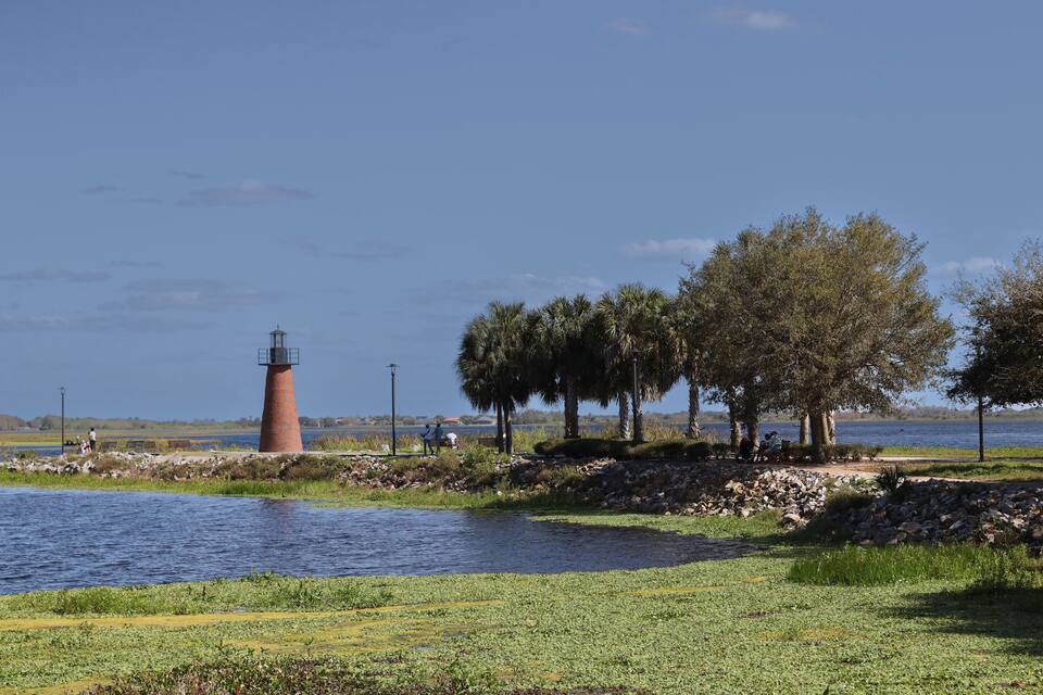 A lighthouse, trees, and a calm lake.