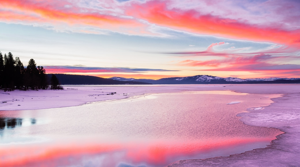 Vibrant sunrise reflecting on open water between ice. Photographed on Lake Almanor in Plumas County, California, USA on a winter morning.