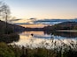 Keystone Lake in Keystone State Park in West Moreland County in the Laurel Highlands of Pennsylvania in the fall right before sunset with the fall foliage and trees reflecting in the water.