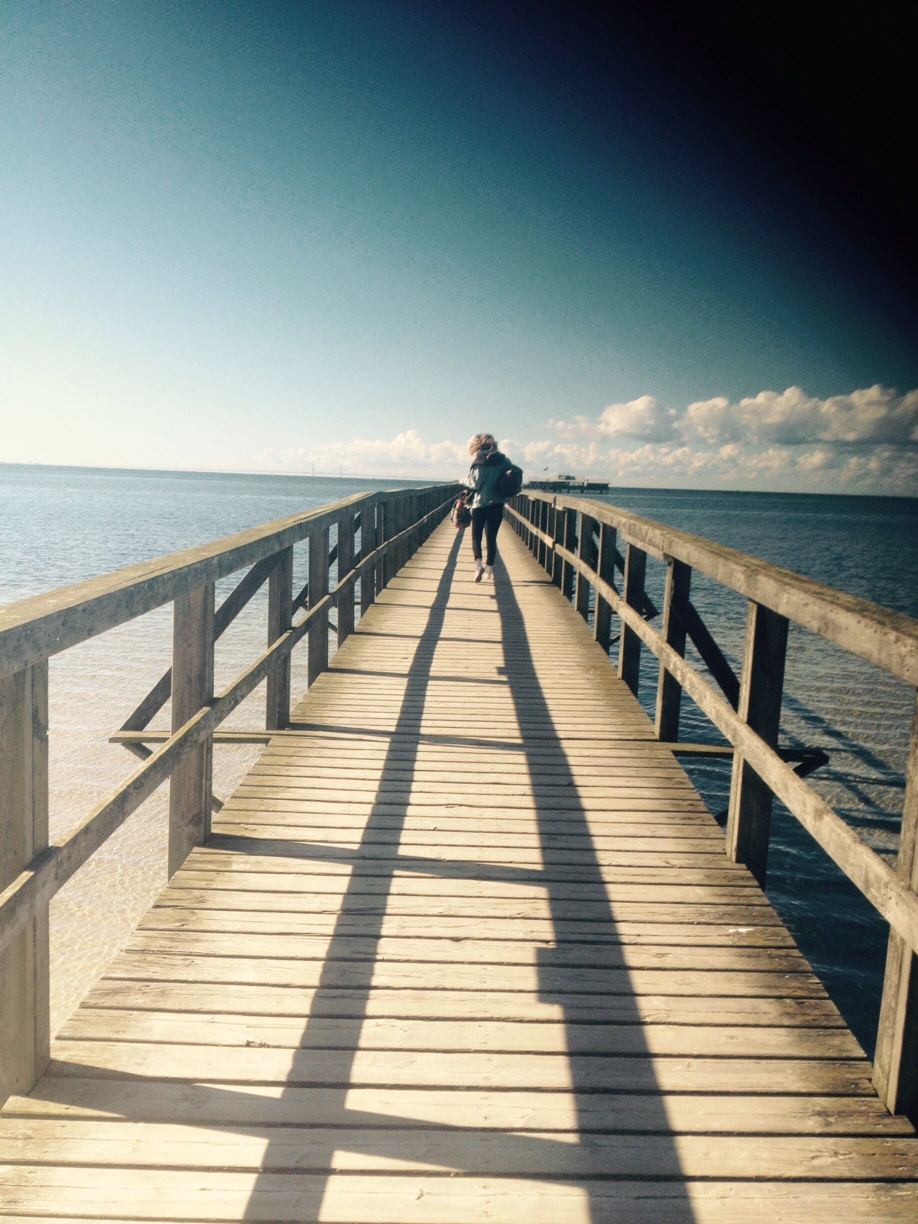 A wooden pier extending into calm waters under a clear sky.