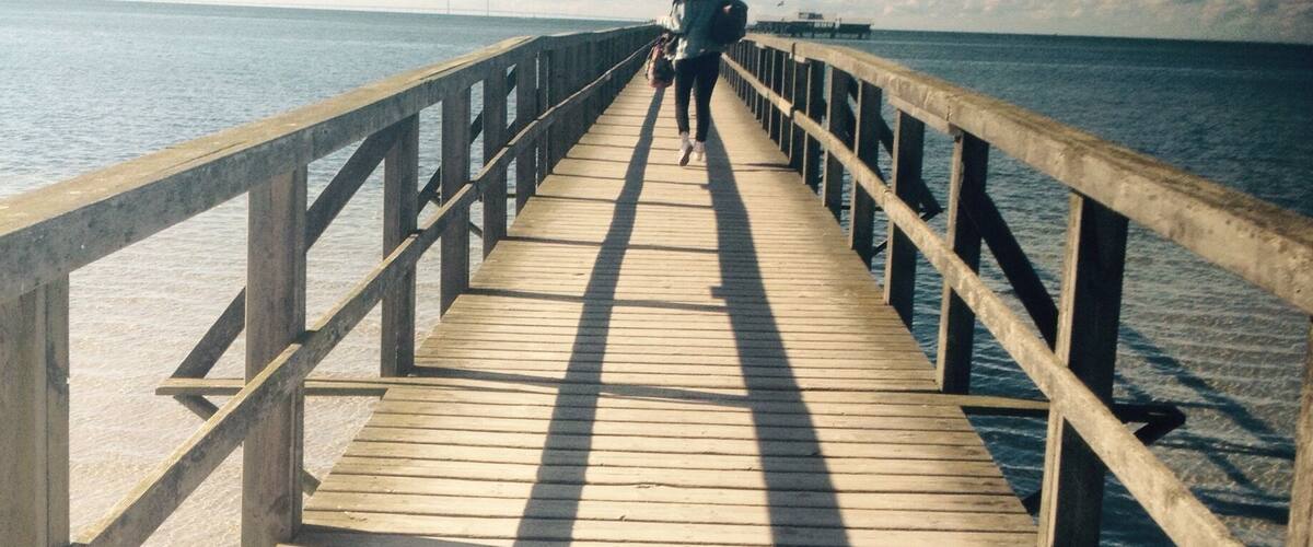 A wooden pier extending into calm waters under a clear sky.