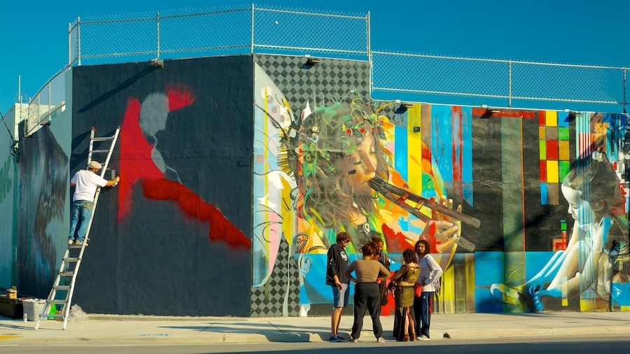 A mural on a building with a ladder and people observing it.