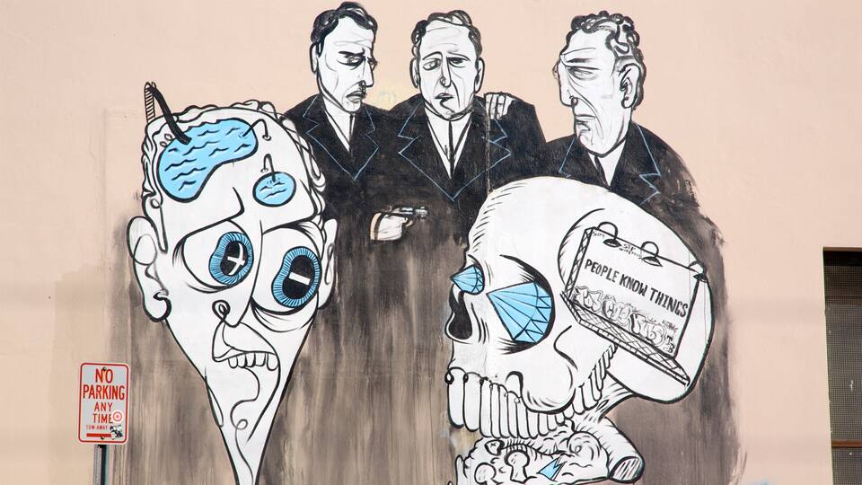 Un mural con tres hombres, uno sosteniendo un cráneo con un cartel que dice 'La gente sabe cosas'.