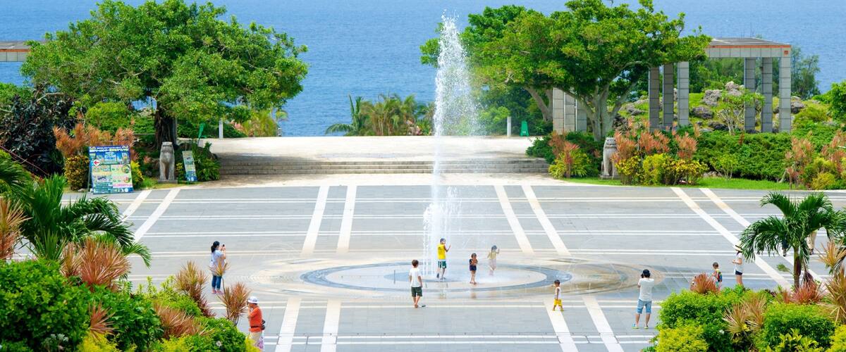 A fountain in a plaza with a view of the ocean and a mountain in the distance.