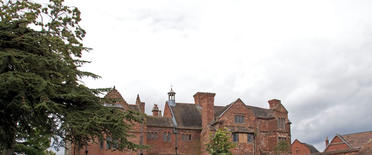 A large brick building with a garden in front.