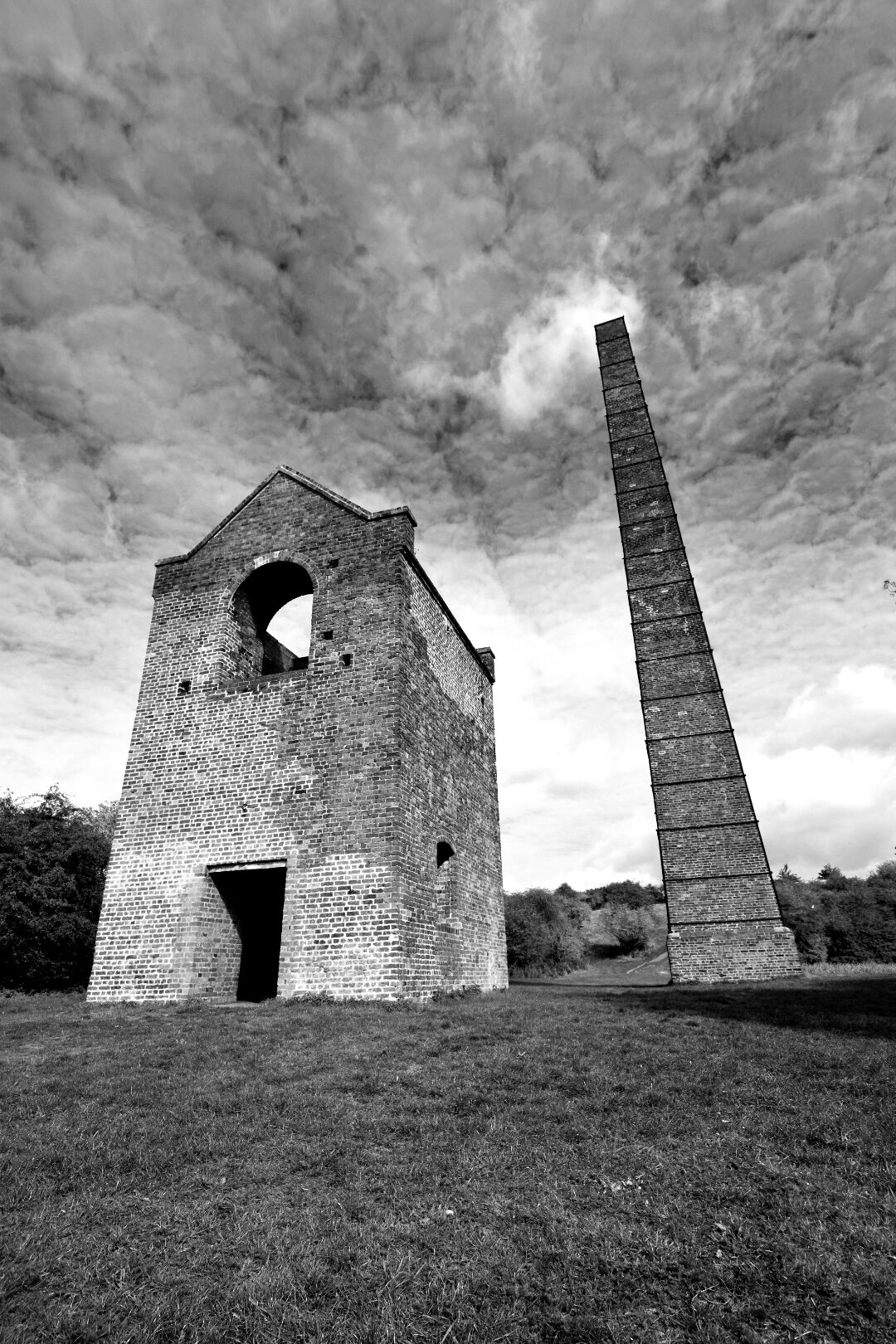 A brick structure with a large arched opening and a tall, narrow tower.