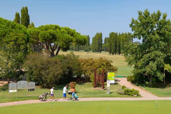 A golf course with lush greenery, trees, and a clear sky.
