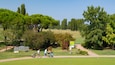 Un campo de golf con abundante vegetación, árboles y cielo despejado.