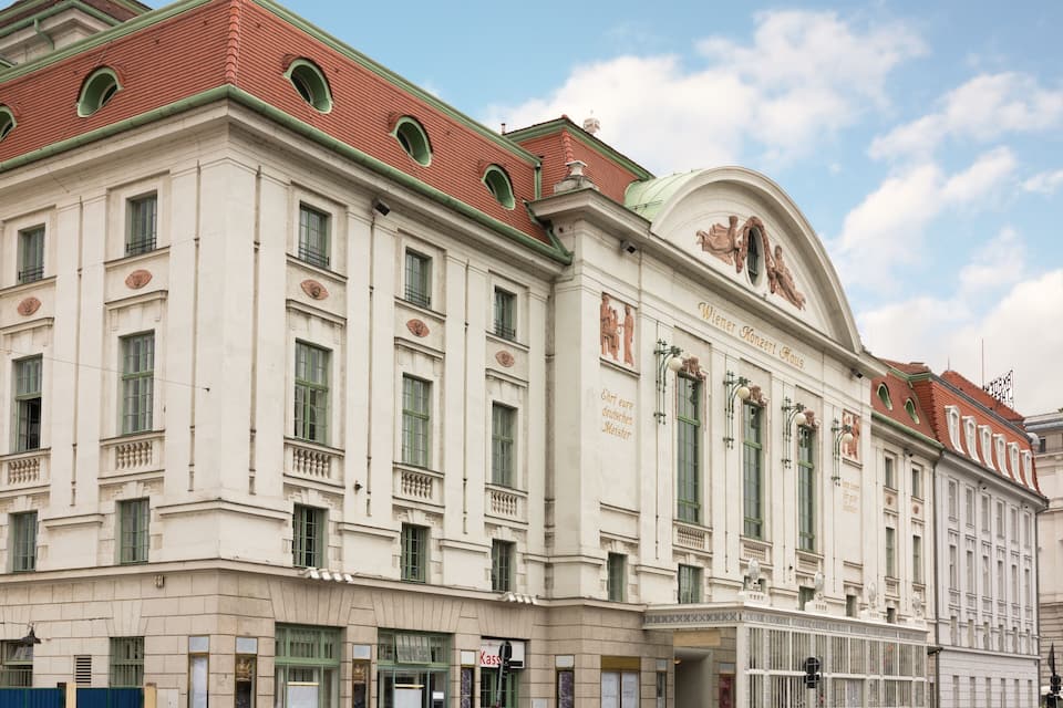 A classical building with arched windows and a red roof.