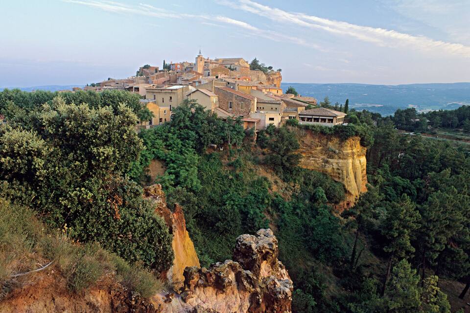 A historic town perched on a cliff with lush greenery and rocky outcrops.