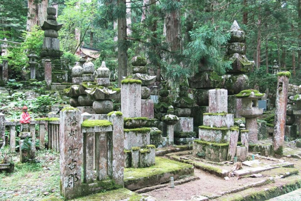 Un cementiri forestal amb monuments de pedra i pagodes.