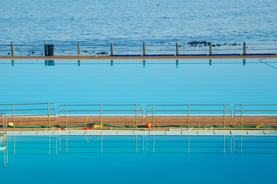 Una piscina con cubierta de madera y barandales metálicos.