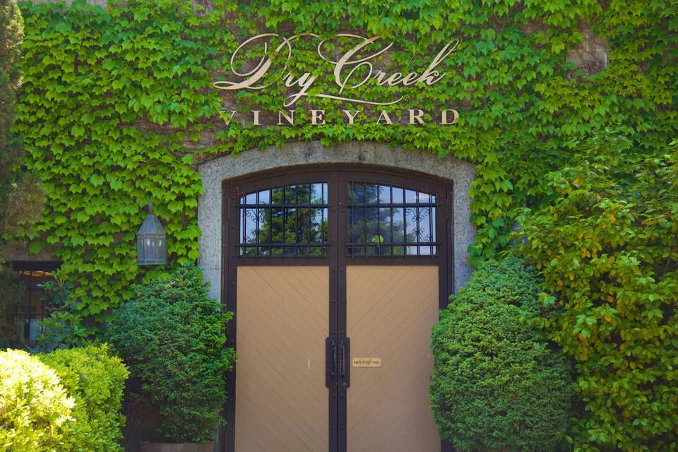 Una puerta con un letrero que dice 'Dry Creek Vineyard' rodeada de hiedra verde exuberante.