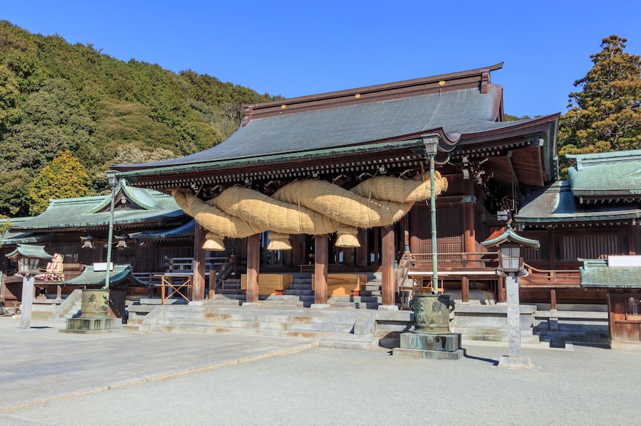 Ein traditioneller japanischer Tempel mit einer großen, hängenden Struktur und einer Bergkulisse.