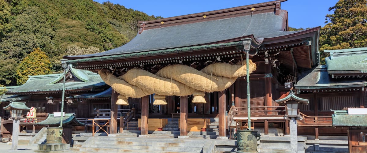 A traditional Japanese temple with a large hanging structure and a mountain backdrop.