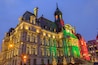A historic building with ornate architecture, a clock tower, and Christmas lights.