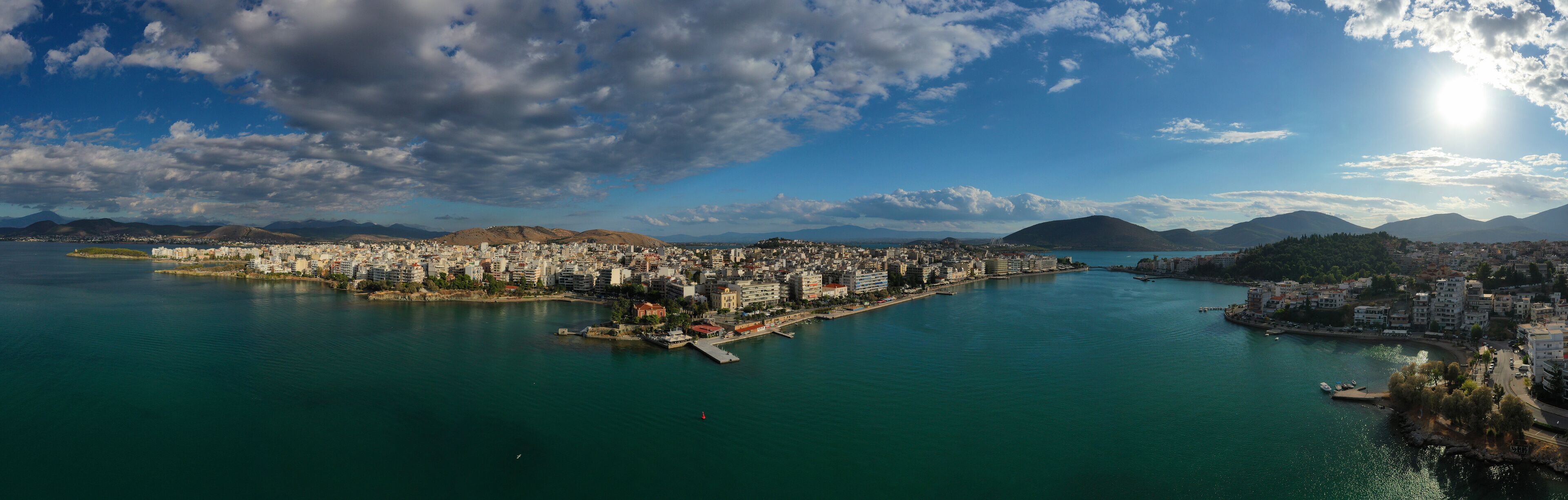 Aerial drone photo of famous seaside town of Halkida or Chalkida with beautiful clouds and deep blue sky featuring old bridge connecting Evia island with mainland Greece