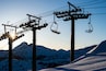 The sunrise silhouettes a chairlift (Chair 6, Cornice Express) at Kirkwood Mountain Resort in the winter in Kirkwood, California.