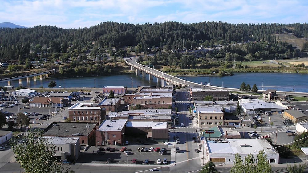 A town with a river, a bridge, and forested hills.