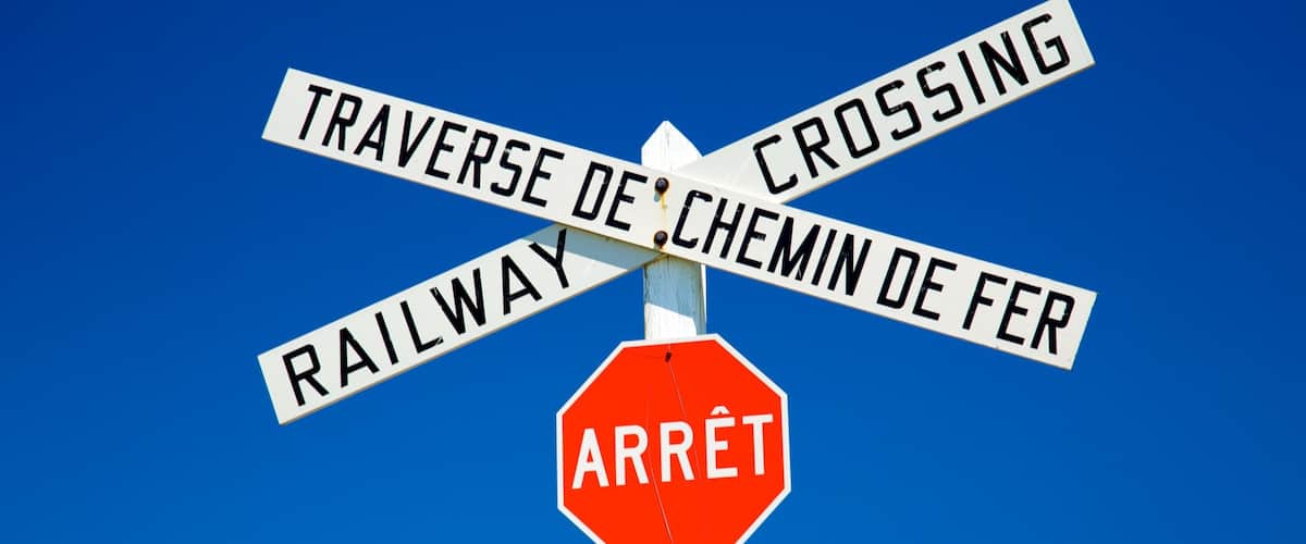 A railway crossing sign with 'ARRÊT' and 'STOP' below it.