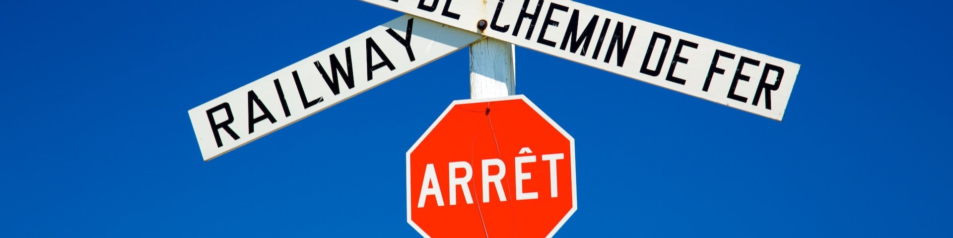 A railway crossing sign with 'ARRÊT' and 'STOP' below it.