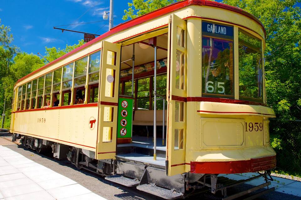 Een klassieke tram, nummer 65, genaamd 'GARLAND', geparkeerd op rails met een groen bord en een rood dak.