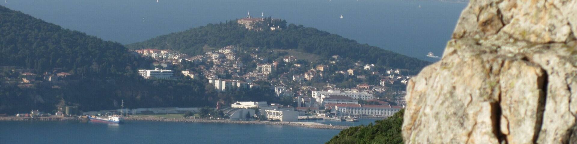 Un pueblo costero con una colina destacada, una masa de agua y un afloramiento rocoso en primer plano.