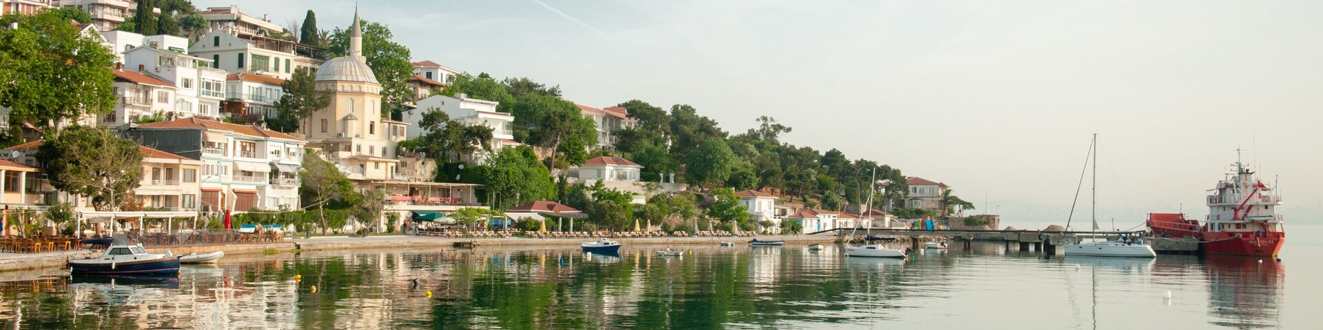 Un río tranquilo con barcos, un puente y una colina con edificios y una estructura en forma de cúpula.
