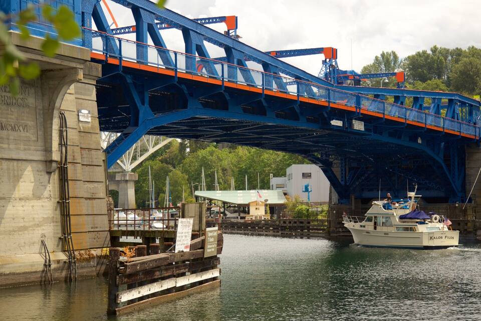 Un pont bleu enjambant une rivière, avec des bateaux et un quai.